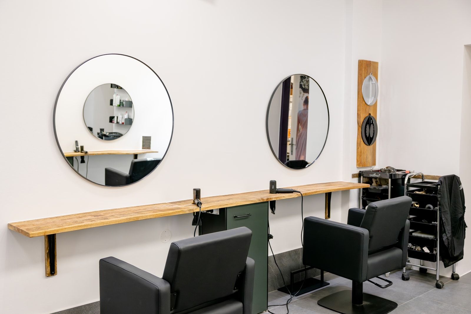 Frisierplätze mit runden Spiegeln und schwarzen Salonsesseln