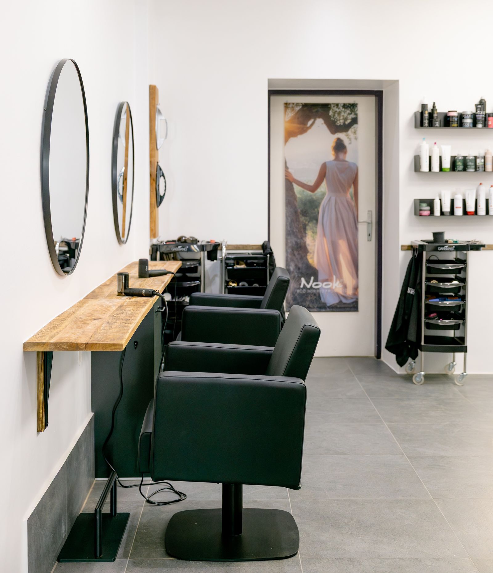 Salonbereich mit Frisierplätzen und Türposter einer Frau im Kleid